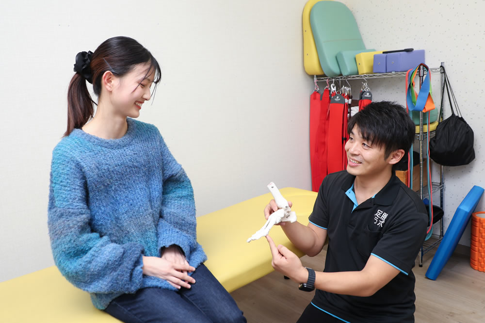 名東区の接骨院 足腰ラボ接骨院で女性の患者様の外反母趾の説明をしている院長