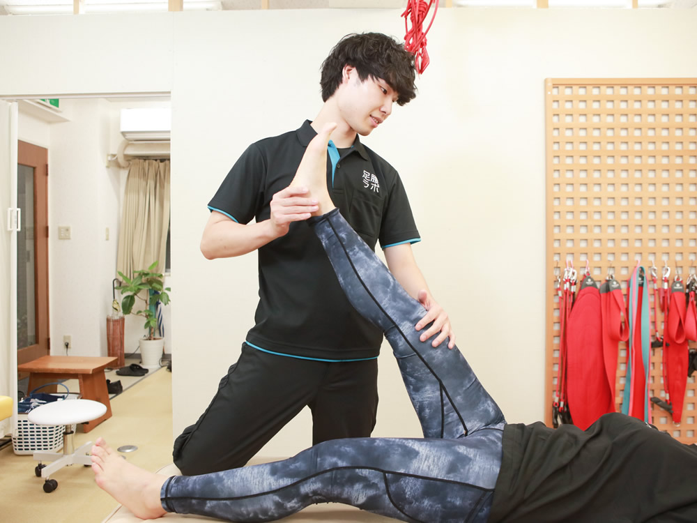 名東区の接骨院 足腰ラボ接骨院でトレーナーに足を伸ばす施術を受ける女性の患者様